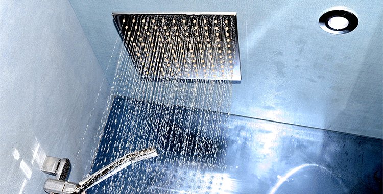 Uma fotografia de um chuveiro eletrônico ligado. 