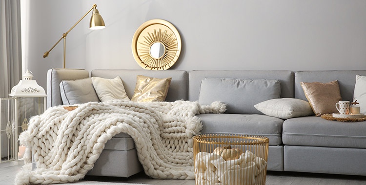 Uma fotografia de um sofá cinza com almofadas e tecido claro.