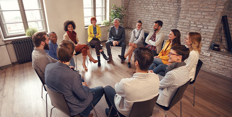 Uma fotografia de pessoas sentados nas cadeiras em um círculo, numa reunião