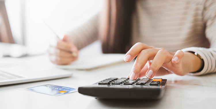 Uma imagem que ilustra uma mulher utilizando uma calculadora representando o que é imposto