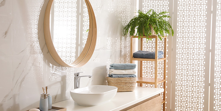 Uma fotografia mostrando Interior elegante do banheiro com espelho redondo, bancada e uma samambaia pendurada.