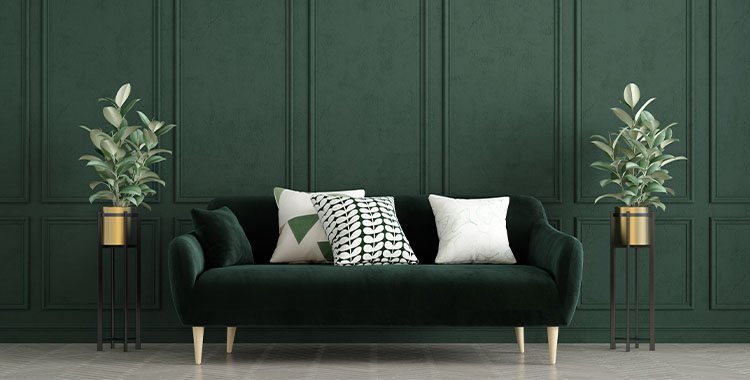 Uma fotografia de decoração elegante em tom verde escuro na parede e sofá com um vaso de planta a esquerda