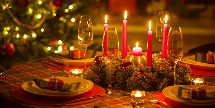 Uma imagem de uma decoração de Natal com velas vermelhas, pratos e talheres